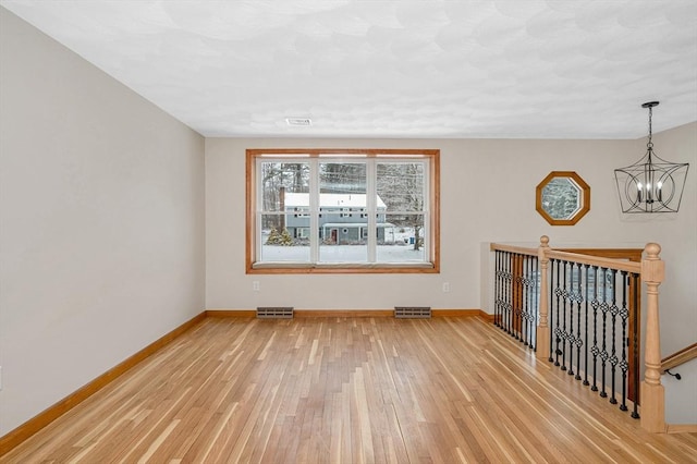 empty room featuring a chandelier and hardwood / wood-style floors