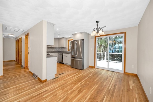 kitchen featuring decorative light fixtures, a chandelier, light hardwood / wood-style flooring, appliances with stainless steel finishes, and backsplash