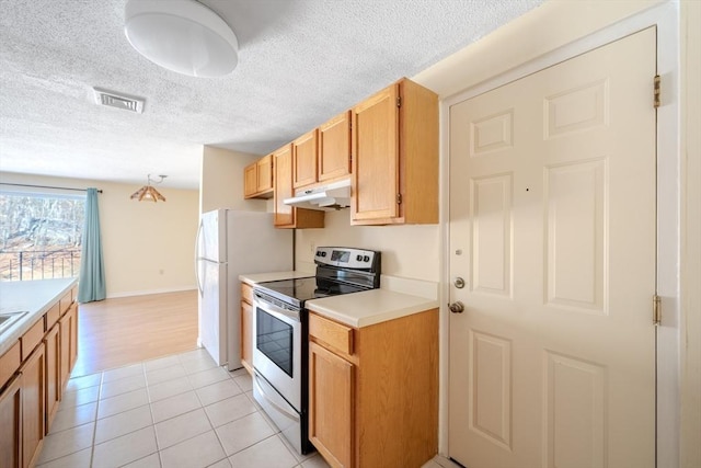 kitchen with pendant lighting, light tile patterned floors, stainless steel range with electric stovetop, white refrigerator, and a textured ceiling