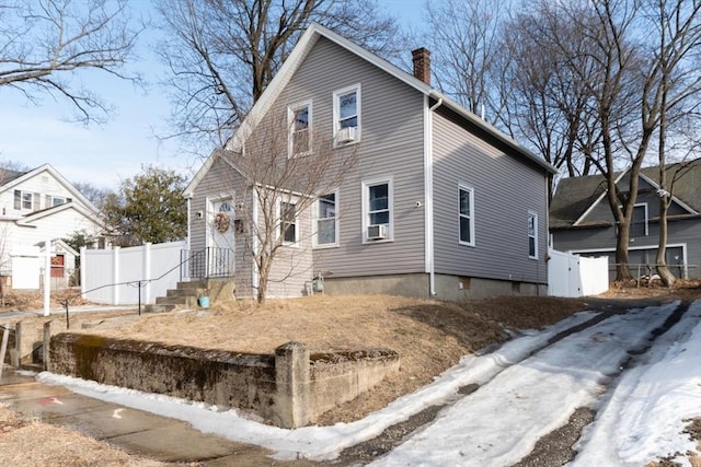 view of front of house featuring cooling unit, fence, and a chimney