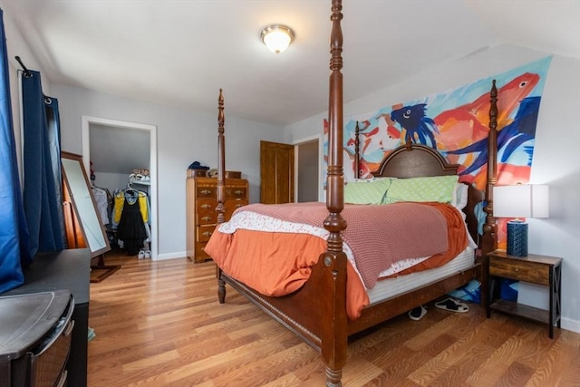 bedroom featuring a closet, light wood-type flooring, a walk in closet, and baseboards