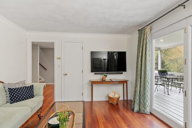 living room featuring wood finished floors, stairway, ornamental molding, and baseboards