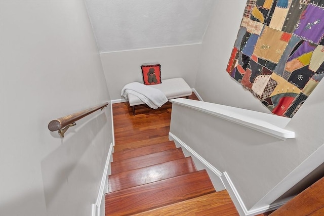 staircase with vaulted ceiling, wood finished floors, and baseboards