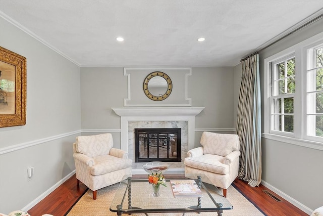 living area with baseboards, wood finished floors, a premium fireplace, recessed lighting, and crown molding