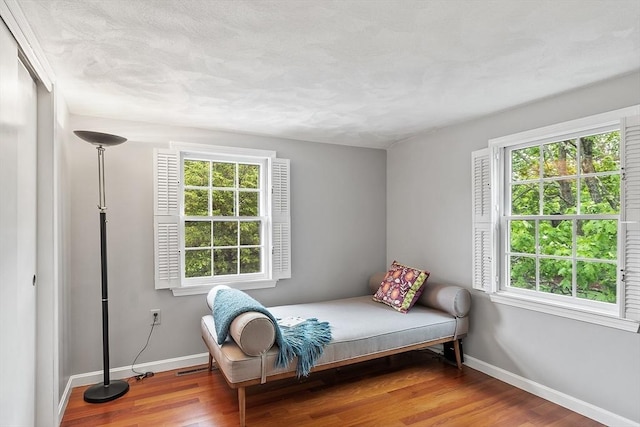 bedroom with baseboards, multiple windows, and wood finished floors