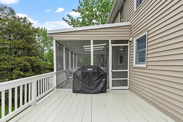 wooden terrace featuring a sunroom and a grill