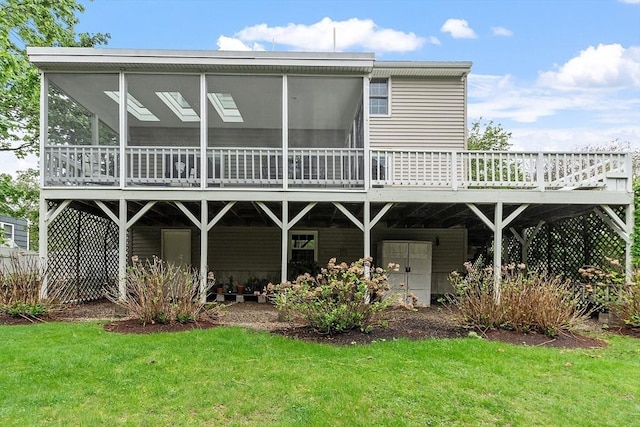 rear view of house with a sunroom, a deck, and a yard