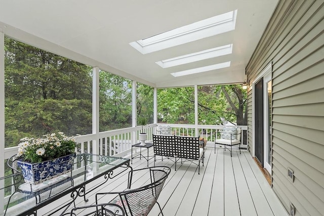 sunroom with a skylight and view of wooded area