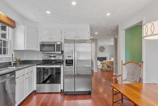 kitchen with appliances with stainless steel finishes, a sink, dark wood finished floors, white cabinets, and recessed lighting