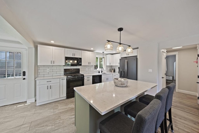 45 Weyham Rd, Weymouth, MA 02191 - kitchen featuring black appliances, backsplash, a breakfast bar, white cabinets, and a sink