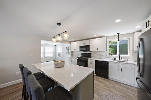 45 Weyham Rd, Weymouth, MA 02191 - kitchen featuring black appliances, a sink, backsplash, a kitchen island, and white cabinetry
