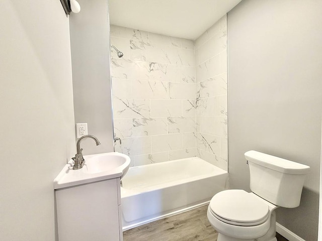 full bathroom with hardwood / wood-style floors, vanity, tiled shower / bath combo, and toilet