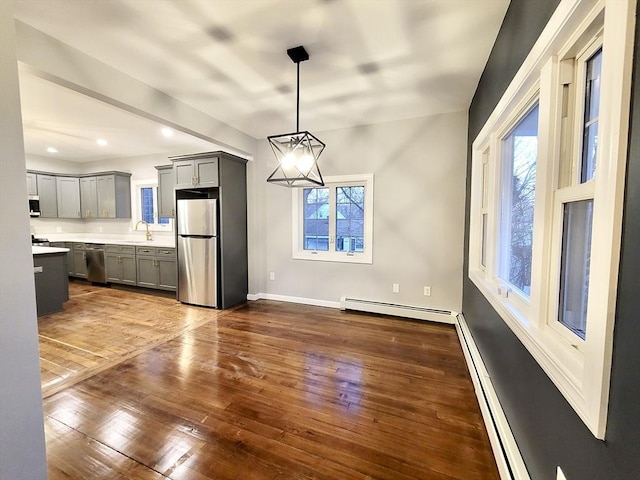 unfurnished dining area featuring dark wood-type flooring, plenty of natural light, a baseboard heating unit, and sink