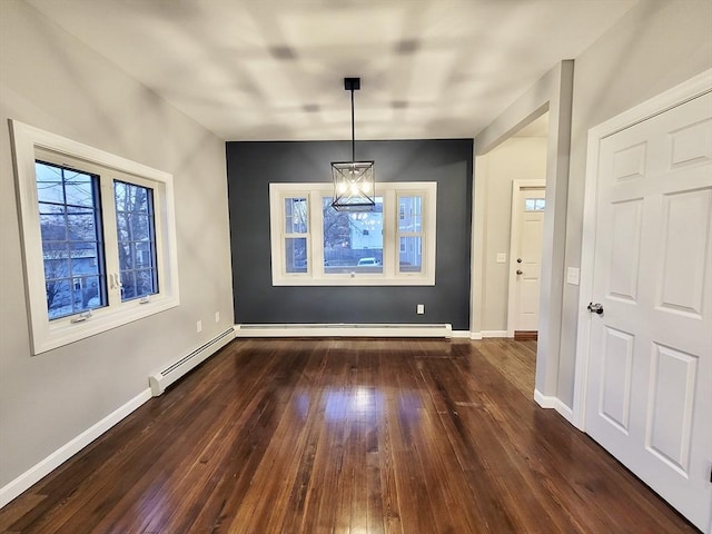 unfurnished dining area featuring dark hardwood / wood-style flooring, baseboard heating, and a chandelier