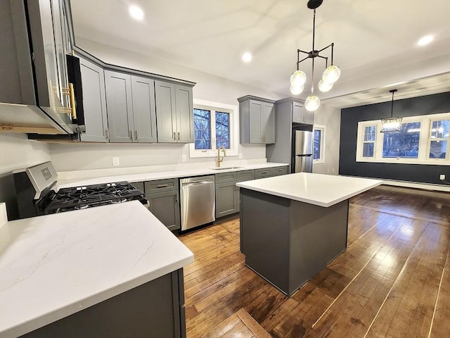 kitchen with a center island, dark wood-type flooring, sink, appliances with stainless steel finishes, and a notable chandelier