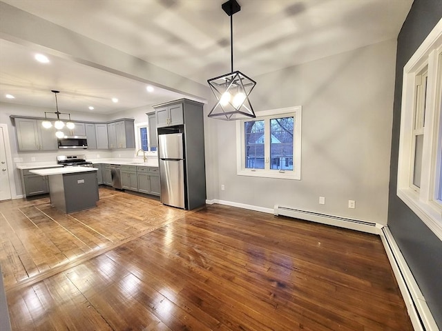 kitchen featuring pendant lighting, a center island, appliances with stainless steel finishes, and a baseboard heating unit