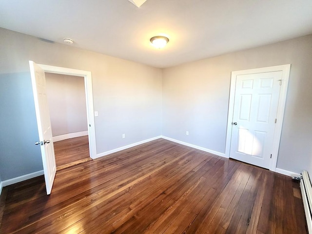 unfurnished room with dark hardwood / wood-style flooring and baseboard heating