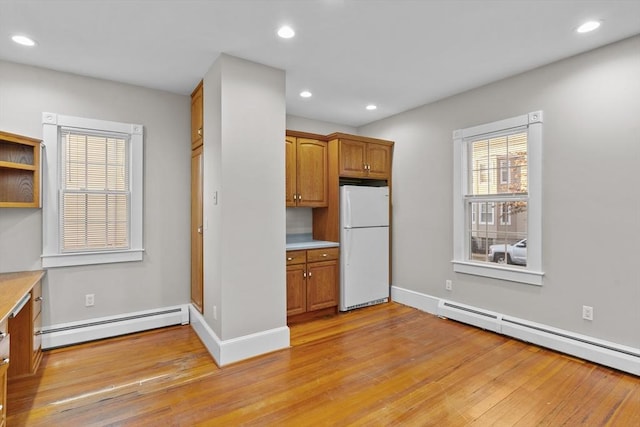 kitchen with built in desk, baseboard heating, light hardwood / wood-style flooring, and white refrigerator