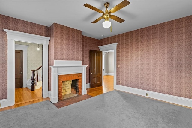 unfurnished living room featuring a brick fireplace, ceiling fan, and light hardwood / wood-style flooring