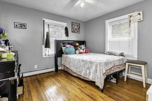 bedroom featuring hardwood / wood-style flooring, a baseboard heating unit, and a ceiling fan