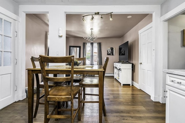 dining space featuring dark wood-type flooring, a chandelier, a baseboard radiator, and baseboards