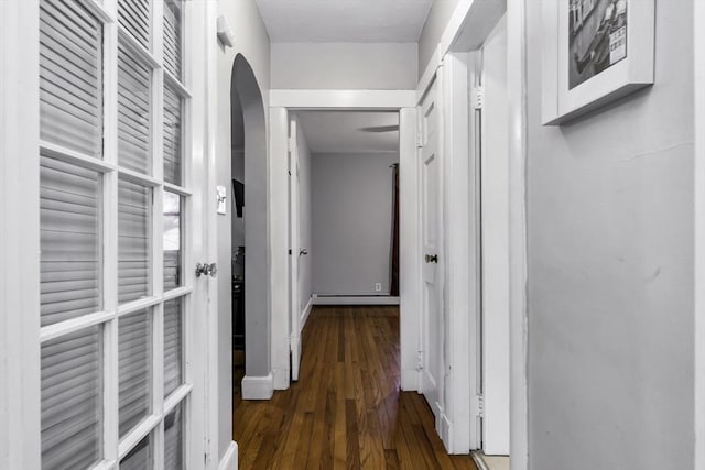 corridor with dark wood-style floors, arched walkways, and baseboards