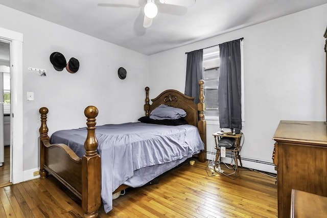bedroom with wood-type flooring, a baseboard radiator, and a ceiling fan