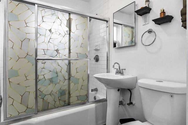 bathroom featuring toilet and combined bath / shower with glass door
