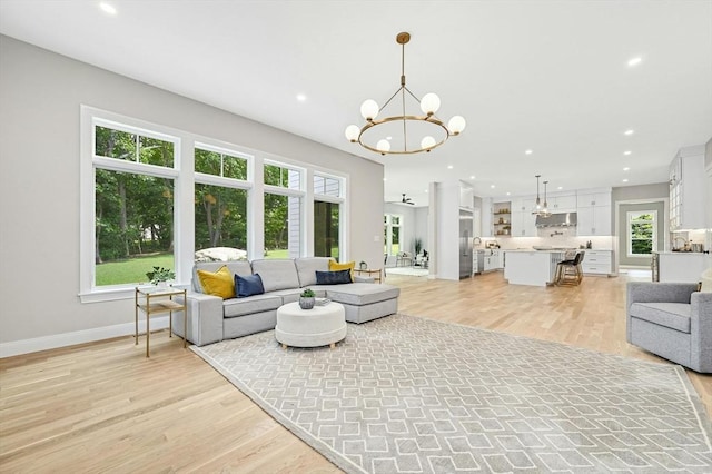 living room featuring light hardwood / wood-style flooring and ceiling fan with notable chandelier