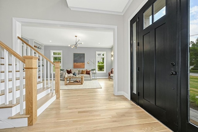 entryway featuring ornamental molding, light hardwood / wood-style floors, and a notable chandelier