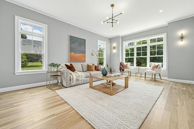 living room featuring a healthy amount of sunlight, light hardwood / wood-style floors, an inviting chandelier, and crown molding