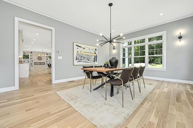 dining space featuring crown molding, light wood-type flooring, and an inviting chandelier