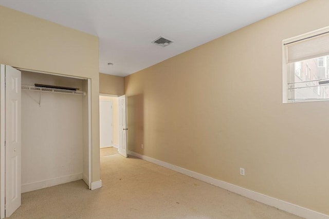 unfurnished bedroom featuring light carpet, a closet, visible vents, and baseboards