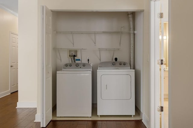 clothes washing area featuring laundry area, baseboards, dark wood finished floors, ornamental molding, and washing machine and clothes dryer