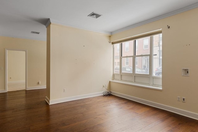 spare room with ornamental molding, visible vents, dark wood finished floors, and baseboards