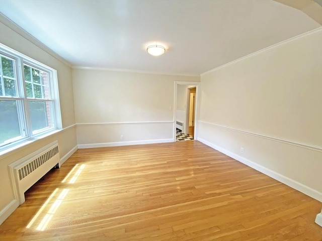 unfurnished room featuring radiator, light wood-style floors, baseboards, and ornamental molding