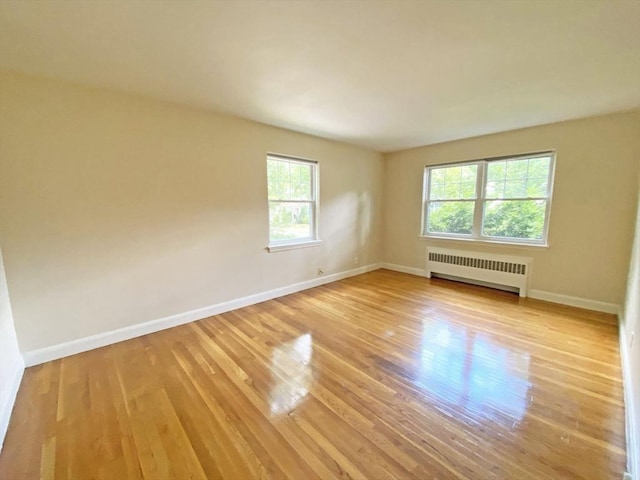 empty room featuring radiator, baseboards, and wood finished floors