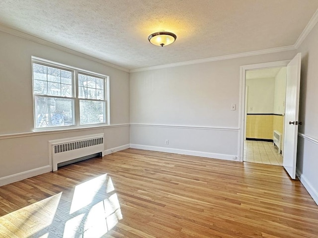 unfurnished room with light wood finished floors, radiator heating unit, ornamental molding, and a textured ceiling