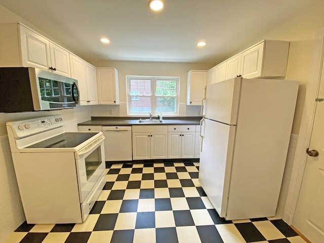 kitchen with white appliances, a sink, white cabinets, tile patterned floors, and dark countertops