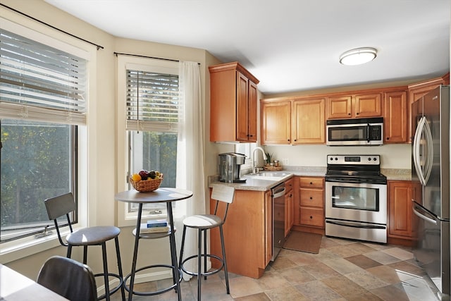 kitchen featuring a healthy amount of sunlight, light stone countertops, sink, and stainless steel appliances