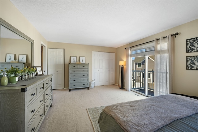 carpeted bedroom with two closets, a textured ceiling, and access to outside