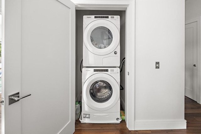 laundry room featuring stacked washer and clothes dryer, wood finished floors, and laundry area