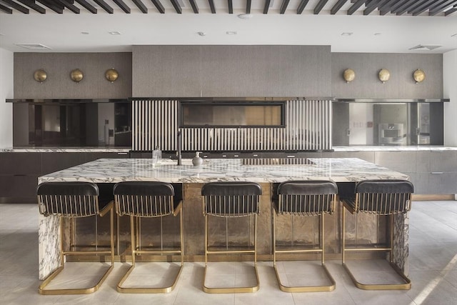 kitchen with a kitchen breakfast bar, modern cabinets, visible vents, and light stone countertops