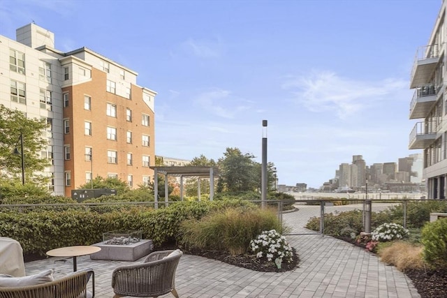 view of home's community with a city view, a patio area, fence, and an outdoor fire pit