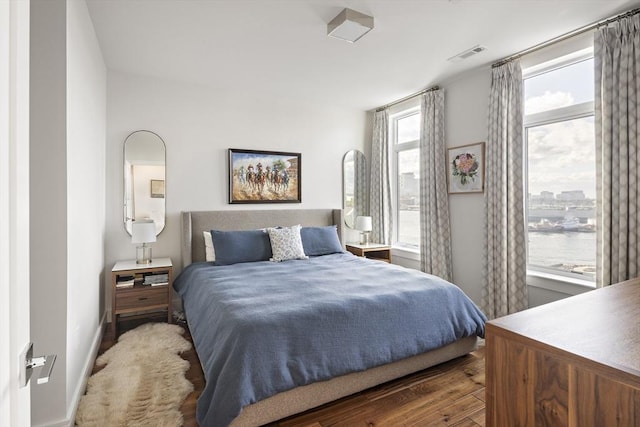 bedroom featuring visible vents, baseboards, and wood finished floors