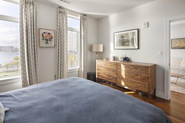 bedroom with visible vents, multiple windows, baseboards, and wood finished floors