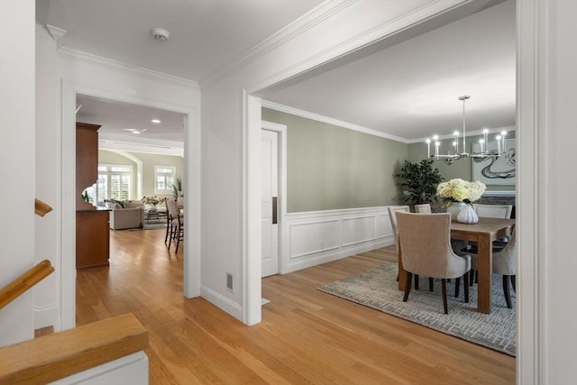 dining area with an inviting chandelier, ornamental molding, and hardwood / wood-style floors