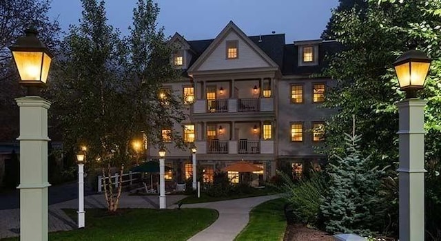 back of property at dusk featuring a balcony