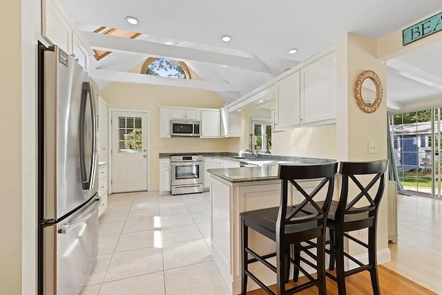 4 Wildwood Ave, Harwich, MA 02645 - kitchen with appliances with stainless steel finishes, a peninsula, white cabinetry, a kitchen bar, and light tile patterned floors