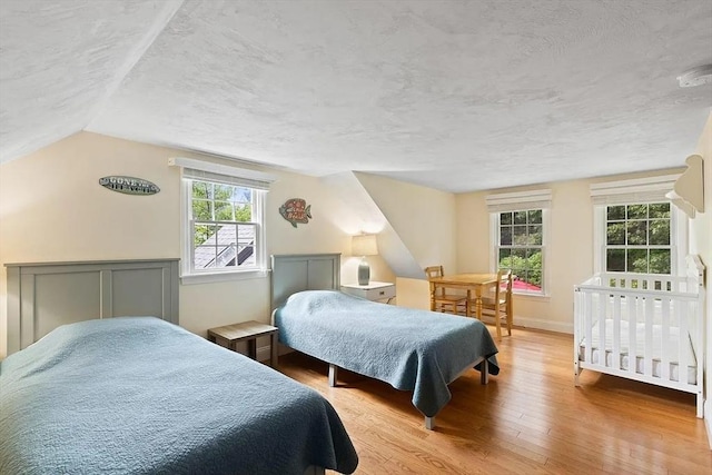 4 Wildwood Ave, Harwich, MA 02645 - bedroom featuring wood finished floors, a textured ceiling, multiple windows, and lofted ceiling